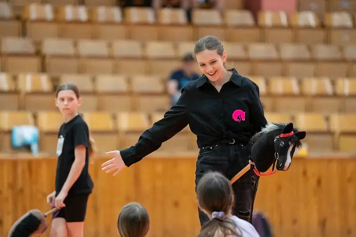 Dimostrazione di Hobby Horsing in una palestra con una donna che tiene un Hobby Horse nero