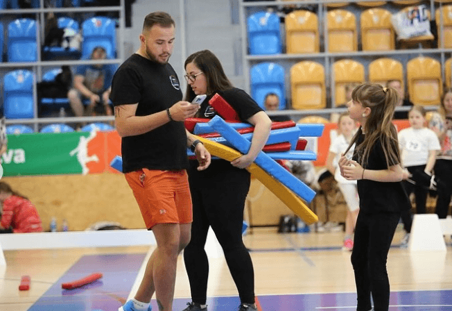 Denny preparing colorful Hobby Horse jumps with a young Hobby Horsing participant in a sports hall