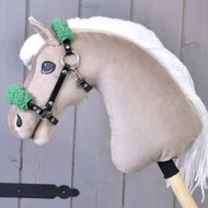 Giocattolo Hobby Horse LarDen con testa in peluche beige, criniera bianca in filato e cavezza nera con pelliccia verde in similpelle. Mostrato davanti a uno sfondo grigio in legno.