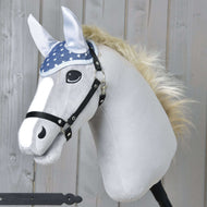 The Hobby Horse LarDen Ear Bonnet Star is a plush stick horse toy with a white face, black bridle, blue star-patterned ear bonnet for fly protection, light mane, and cartoon eyes, shown against a wooden background.