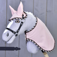 Set Abby by Hobby Horse LarDen is a gray and white stuffed hobby horse with a plush mane, embroidered eye, and pink bridle and blanket set, displayed against a light wooden wall.