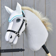 A close-up of a gray plush hobby horse by Hobby Horse LarDen with a white mane, black bridle, and the Ear bonnet Glitter Cuties for fly protection, mounted on a wooden stick in front of a wooden fence.