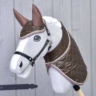 The Hobby Horse LarDen Set Thermo Chocolate features a gray hobby horse with large eyes, dressed in a shiny brown quilted blanket and matching ear bonnet, mounted on a stick against a light wooden wall.