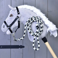 The Hobby Horse LarDen Hobby Horse features a gray plush head with a white mane, black bridle, and includes a black-and-white braided lead rope. Essential horse equipment, displayed against a gray wooden background.