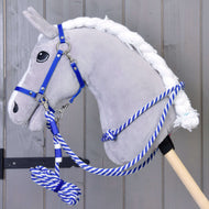 Set Start blu (cavezza, guinzaglio, redini, redini a collare) di Hobby Horse LarDen su Hobby Horse di peluche grigio con lunghina blu e bianca su bastone in legno, davanti a una parete in legno grigio.