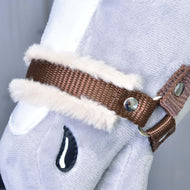 Primo piano della "Cavezza marrone con pelliccia" di Hobby Horse LarDen, accessorio per Hobby Horse in peluche grigio chiaro con cavezza marrone, bordo in ecopelliccia bianca, borchie metalliche e dettaglio nero cucito a forma di goccia.
