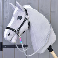 Hobby Horse LarDen Redini Manhattan con Hobby Horse grigio, criniera bianca, cavezza nera, redini artigianali e bastone in legno, mostrato davanti a una parete in legno grigio.