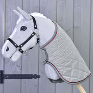 Un Hobby Horse di peluche grigio di Hobby Horse LarDen con briglia nera e Coperta Silver Eleganza davanti a una parete in legno con pannelli verticali.