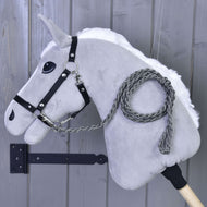 The Hobby Horse LarDen "Hobby Horse - Knitted Lead Rope Graphite" features a gray plush head, black bridle, and hand-knitted graphite lead rope on a wooden stick, shown against a gray wooden wall.