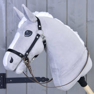 A gray hobby horse by Hobby Horse LarDen features a white mane, black bitless bridle, and light brown reins, mounted on a wooden stick in front of a gray wooden fence.