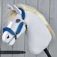 Hobby Horse LarDen Cavezza in pelliccia Teddy Petrol su Hobby Horse di peluche con tessuto grigio chiaro, muso bianco, criniera bionda e cavezza blu in similpelle su bastone nero, davanti a uno sfondo in legno.
