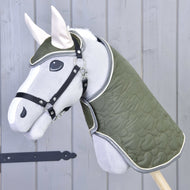 Set Olivetti di Hobby Horse LarDen con Hobby Horse grigio, coperta trapuntata verde e briglia, cavezza nera, orecchie bianche e accessori eleganti, mostrato davanti a una parete di legno grigio chiaro.