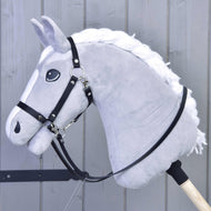 Redini nere in similpelle di Hobby Horse LarDen su un Hobby Horse grigio in peluche con criniera bianca, briglia senza morso e redini nere in similpelle di qualità su un bastone di legno, mostrato davanti a pannelli in legno grigio.