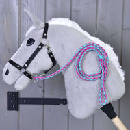 Hobby Horse - Corda guida lavorata a maglia Pinkie-Blue di Hobby Horse LarDen con corpo in peluche grigio, briglia nera, criniera bianca e corda guida intrecciata rosa e verde petrolio, appeso a una parete di legno. Bastone incluso.