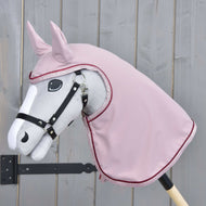 Hobby Horse LarDen grigio montato su bastone di legno, con briglia nera e Impermeabile Veloria rosa sulla testa e sul collo, posizionato davanti a una staccionata di legno chiaro.