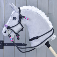 The Rope set Princess by Hobby Horse LarDen features a gray hobby horse with a white mane, detailed black halter and reins, plus pink and turquoise accents, mounted on a wooden stick against a gray plank background.