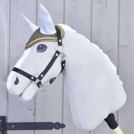 A Hobby Horse LarDen plush hobby horse on a stick with a white mane, gray face, black bridle, and embroidered eye features the Ear Bonnet Sport—a green ear bonnet with orange trim—against a light wooden background.