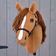 Hobby Horse Wendy con Cavezza Nera di Hobby Horse LarDen presenta una testa in peluche marrone, criniera intrecciata in filato marrone, striscia bianca sul muso e cavezza nera, ispirata a una cavalla saura e mostrata su sfondo di legno grigio.