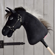 Hobby Horse Bond con cavezza nera di Hobby Horse LarDen, Hobby Horse nero in peluche con criniera bianca, cavezza nera e redini su bastone di legno, esposto davanti a una parete in legno chiaro, perfetto per ogni fan di Hobby Horse Bond.
