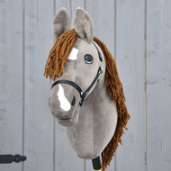 Hobby Horse LarDen Hobby Horse Chanell con Cavezza nera con mantello grigio, criniera in filato marrone, macchie bianche sul muso e grandi occhi espressivi, esposto davanti a uno sfondo di legno grigio.