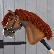 Hobby Horse Cooper con cavezza nera di Hobby Horse LarDen, con testa marrone in tessuto, criniera in filato e una lista bianca sul naso, montato su un bastone di legno. Modellato per ricordare un elegante cavallo sportivo, è perfetto per avventure di dressage di fantasia ed è fotografato qui davanti a uno sfondo di legno grigio.