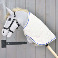 Hobby Horse LarDen Coperta Crema Perla su un Hobby Horse di peluche con testa grigia, briglia nera e coperta crema perla con bordo blu su un bastone di legno, esposto davanti a una parete in legno grigio.