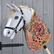 Hobby Horse LarDen Coperta Jungle con Hobby Horse in peluche dalla testa grigia, briglia nera e corpo con coperta colorata, ideale per il gioco immaginativo o il primo addestramento del cavallo, mostrato su sfondo di pannelli in legno.