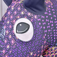 Primo piano della Tuta protettiva Hobby Horse Mandala (Lycra) di Hobby Horse LarDen che mostra il grande occhio ricamato e il tessuto viola con motivi geometrici e a rombi colorati; in alto si vede un orecchio scuro.
