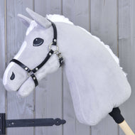 Hobby Horse di peluche grigio di Hobby Horse LarDen con criniera bianca e Cavezza - similpelle nera, montato su un bastone di legno davanti a uno sfondo con pannelli di legno.
