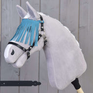 Hobby Horse LarDen grigio con cavezza nera con frange turchesi davanti a una parete di legno.