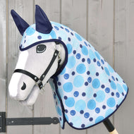Hobby Horse LarDen Impermeabile Bubbles con muso bianco, briglia nera, orecchie blu e coperta azzurro chiaro a pois con accessori per tutte le condizioni meteo su un bastone di legno, esposto davanti a una parete di legno.