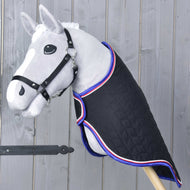 Un Hobby Horse grigio con briglia nera presenta la Coperta da Viaggio Luxury di Hobby Horse LarDen, trapuntata nera con finiture rosse, bianche e blu, posizionato su sfondo di parete in legno.