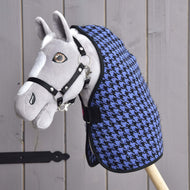 Hobby Horse grigio in peluche con briglia nera e Coperta da scuderia Blu Hobby Horse LarDen con motivo pied-de-poule blu e nero, montato su un bastone di legno e posizionato davanti a una parete di assi di legno.