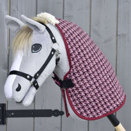 Hobby Horse grigio con briglia nera che indossa la Coperta da Scuderia Magia Invernale di Hobby Horse LarDen con motivo pied-de-poule rosa, realizzata in morbido PES, posizionato davanti a uno sfondo in legno grigio chiaro.