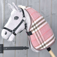 The Hobby Horse LarDen "Stable Blanket Lady" is a gray plush hobby horse with a pink and brown plaid blanket and black bridle on a wooden stick, set against a gray wooden background.