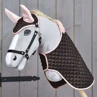 Hobby Horse LarDen Set Termico Sweety con peluche Hobby Horse con briglia, vestito con coperta trapuntata marrone e rosa e cuffietta coordinata, esposto su sfondo in legno.