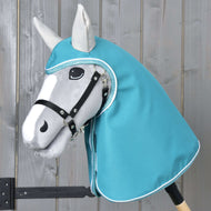 The Hobby Horse LarDen Raincoat Turquoise is a gray hobby horse with a black bridle and turquoise raincoat-style hood, featuring a realistic-shaped face with black and white details, set against a light wooden background.