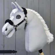 Hobby Horse LarDen Black Halter with Black Fur su un cavallo in peluche grigio chiaro con cavezza nera in similpelle e grandi occhi ricamati, mostrato su sfondo in legno grigio.