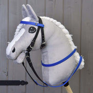 Hobby Horse in peluche di Hobby Horse LarDen con muso grigio, criniera bianca e redini gommate blu, montato su un bastone di legno e posizionato davanti a pannelli in legno.