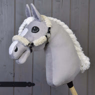 Hobby Horse LarDen con Hobby Horse grigio in peluche con cavezza nera con pelliccia completa e dettagli in similpelle, montato su un bastone di legno davanti a uno sfondo di assi in legno.