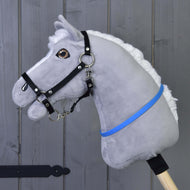 Hobby Horse redini a collare blu (taglia S) di Hobby Horse LarDen su corpo di peluche grigio con criniera bianca, briglia nera e nastro blu-viola su bastone in legno, mostrato davanti a una parete in legno grigio.