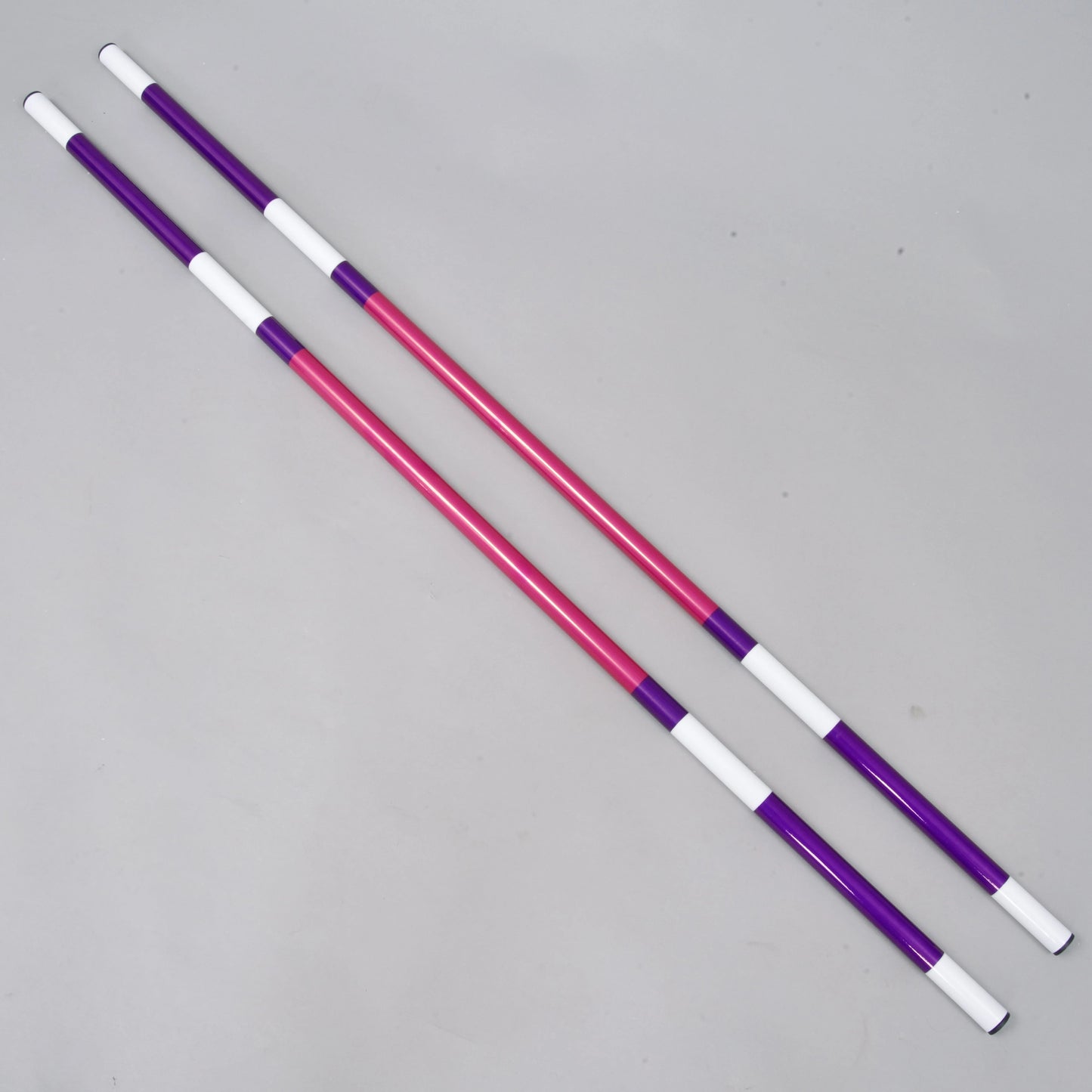 Two Hobby Horse LarDen Jump pole pink-purple 2 pcs, each lightweight with 32 mm diameter and alternating purple, pink, and white sections, lay parallel on a plain light grey background. Coated PVC ensures easy handling.