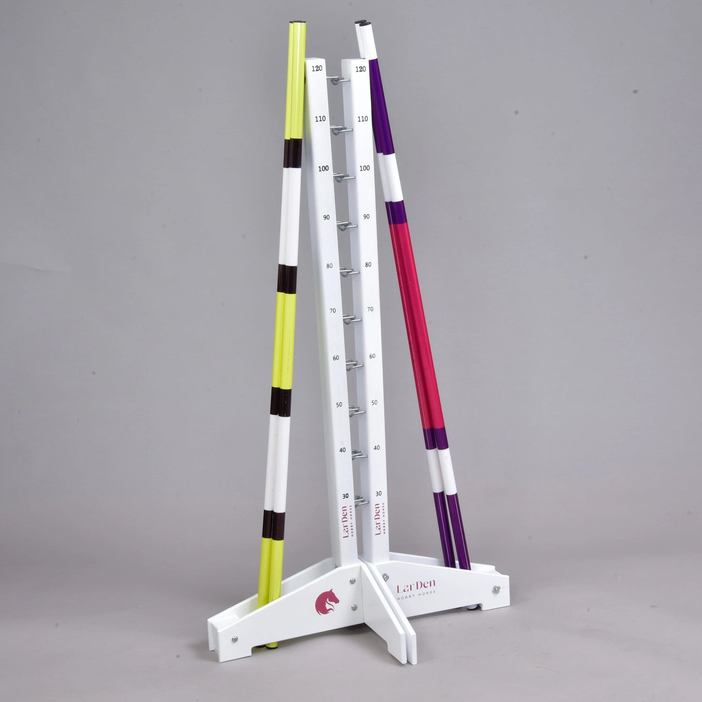 The Hobby Horse LarDen Jump set for Hobby Horsing features adjustable jumps with height markers and includes two colored poles—one yellow with black stripes and one pink with purple stripes—shown against a plain gray background. Perfect for cavaletti or hobby horsing fun.