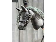 Primo piano di Hobby Horse Little Prince con capezza nera - taglia XS di Hobby Horse LarDen, con testa in tessuto grigio, capezza nera, occhi a bottone e criniera in filato su sfondo di legno sfocato.