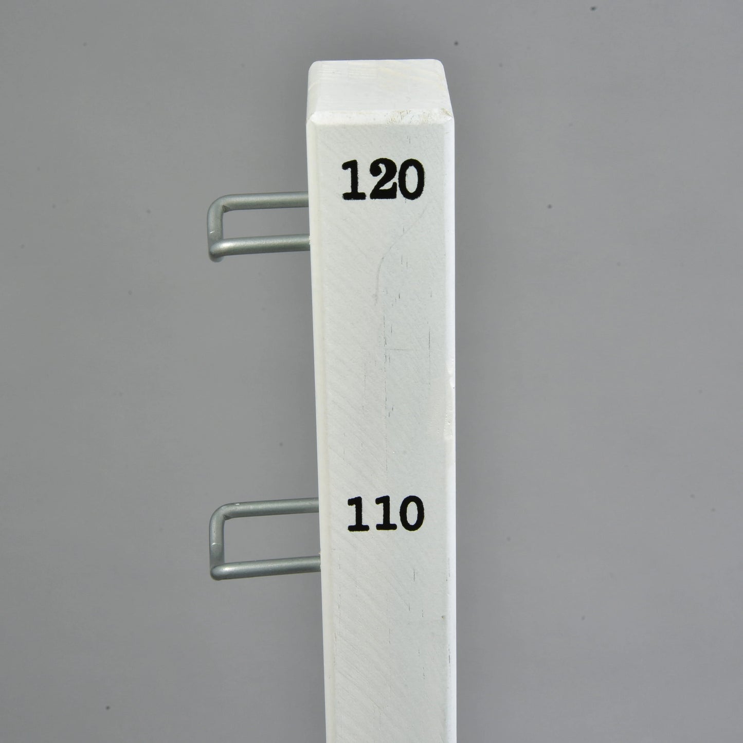 The Hobby Horse LarDen Jump 120 cm / 47 inch with Extra Poles is a white vertical post with black numbers 110 and 120, two metal hooks on the left side, ideal for adjustable indoor or outdoor hobby horsing, shown against a plain gray background.