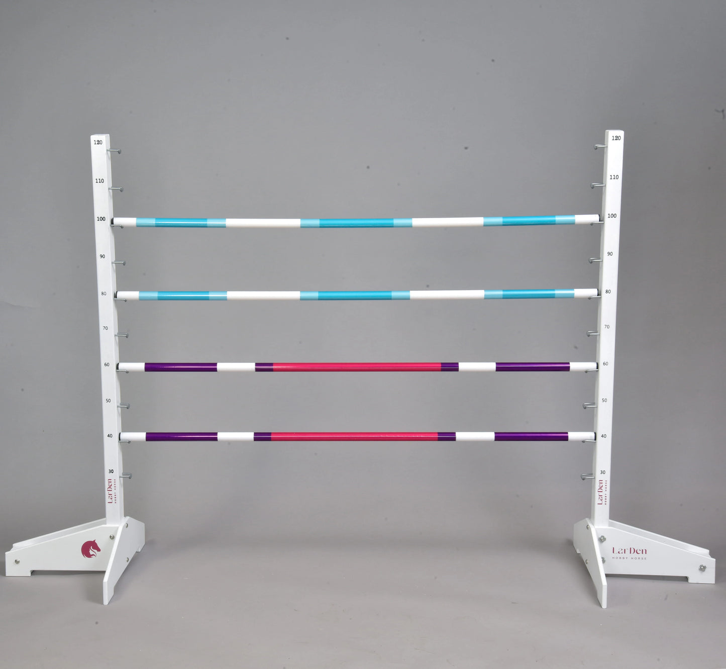 The Hobby Horse LarDen Jump 120 cm / 47 inch with Extra Poles features five striped poles in blue, white, purple, and red, two adjustable white stands, and is suitable for indoor or outdoor hobby horsing. Plain grey background.