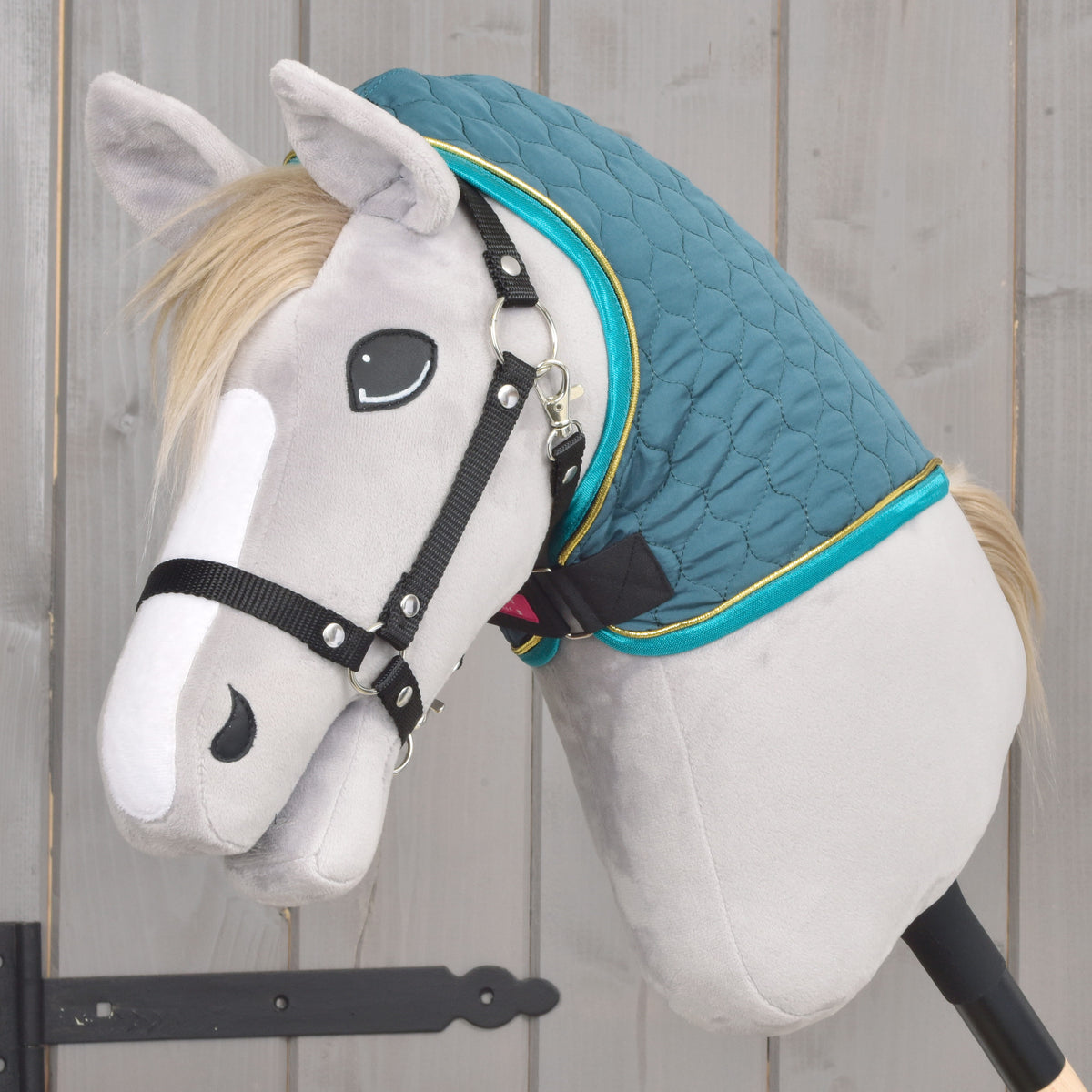 Coperta Hobby Horse verde trapuntata con copricollo rimovibile vista di lato su un Hobby Horse grigio