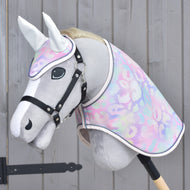 Grey Hobby Horse wearing the pastel leopard print ear bonnet and blanket with a black halter against a grey wooden wall
