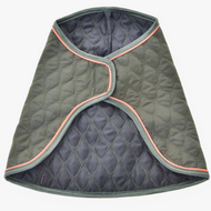Coperta Sport di Hobby Horse LarDen, cappottino trapuntato verde scuro con bordo grigio e profilo arancione chiaro, ispirato alle coperte protettive da cavallo. Mostrato aperto e disteso, presenta un motivo trapuntato a rombi e bordi curvi.