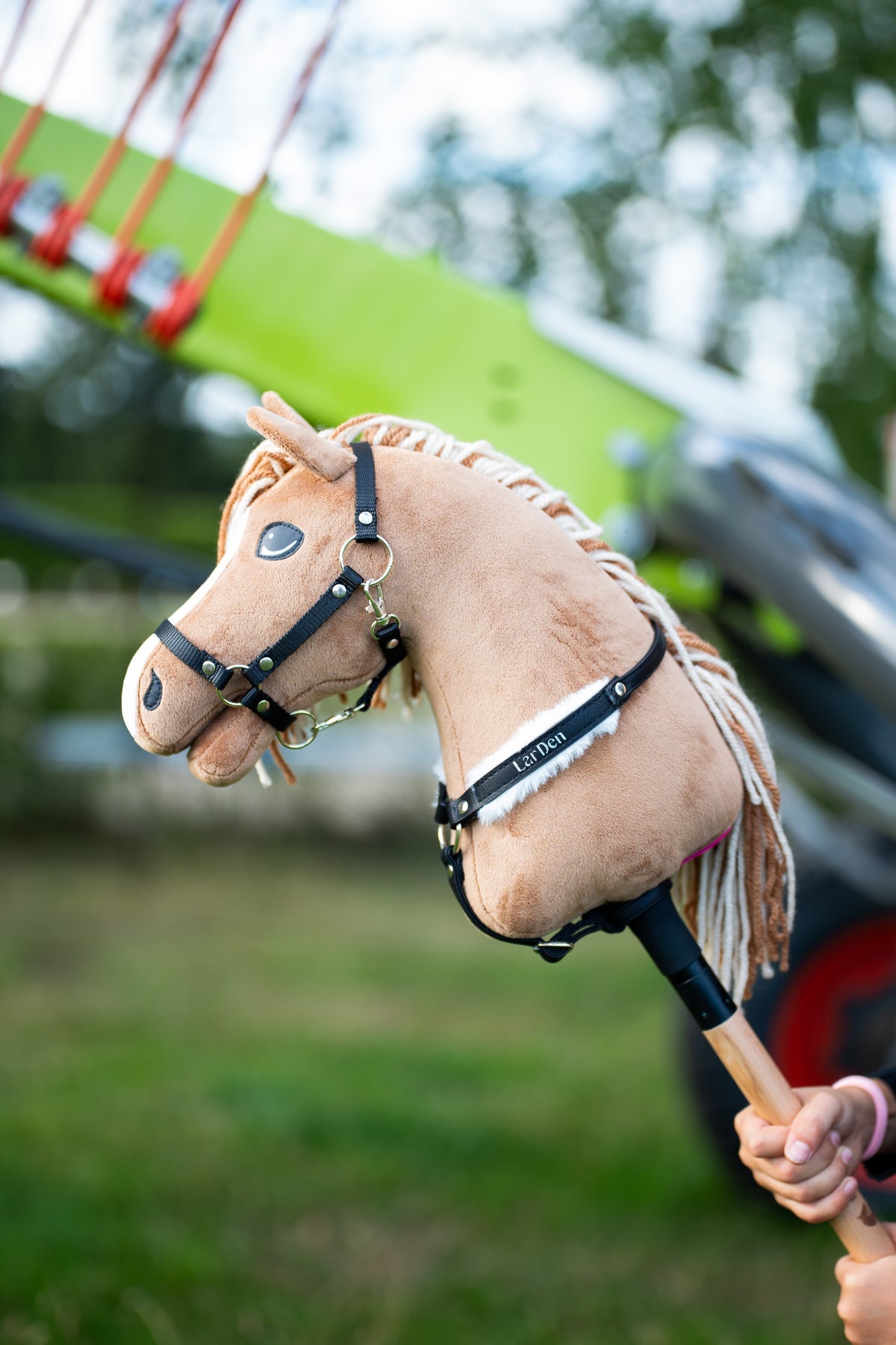 Sandy Hobby Horse wearing a black leatherette breastgirth with white fur trim outdoors